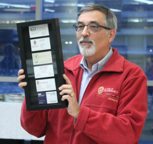 Greg Higby holds a framed case featuring his business cards over the years.