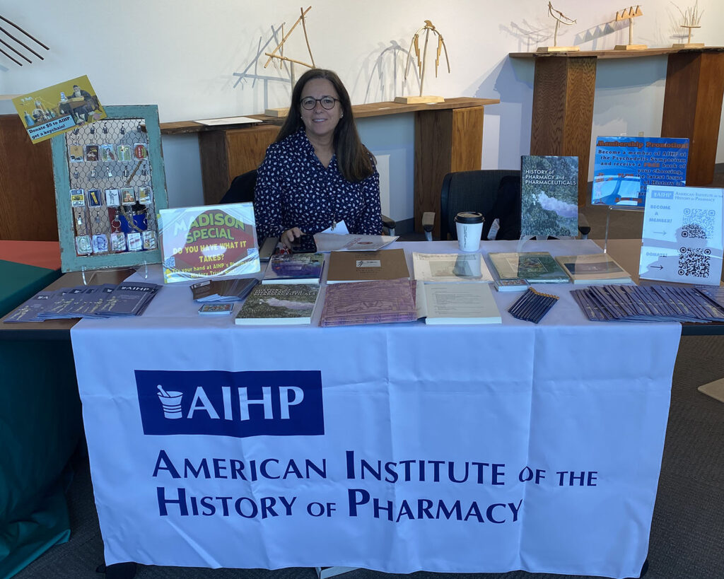 AIHP staff member Beth Fisher sits at a table at the Psychedelic Symposium.